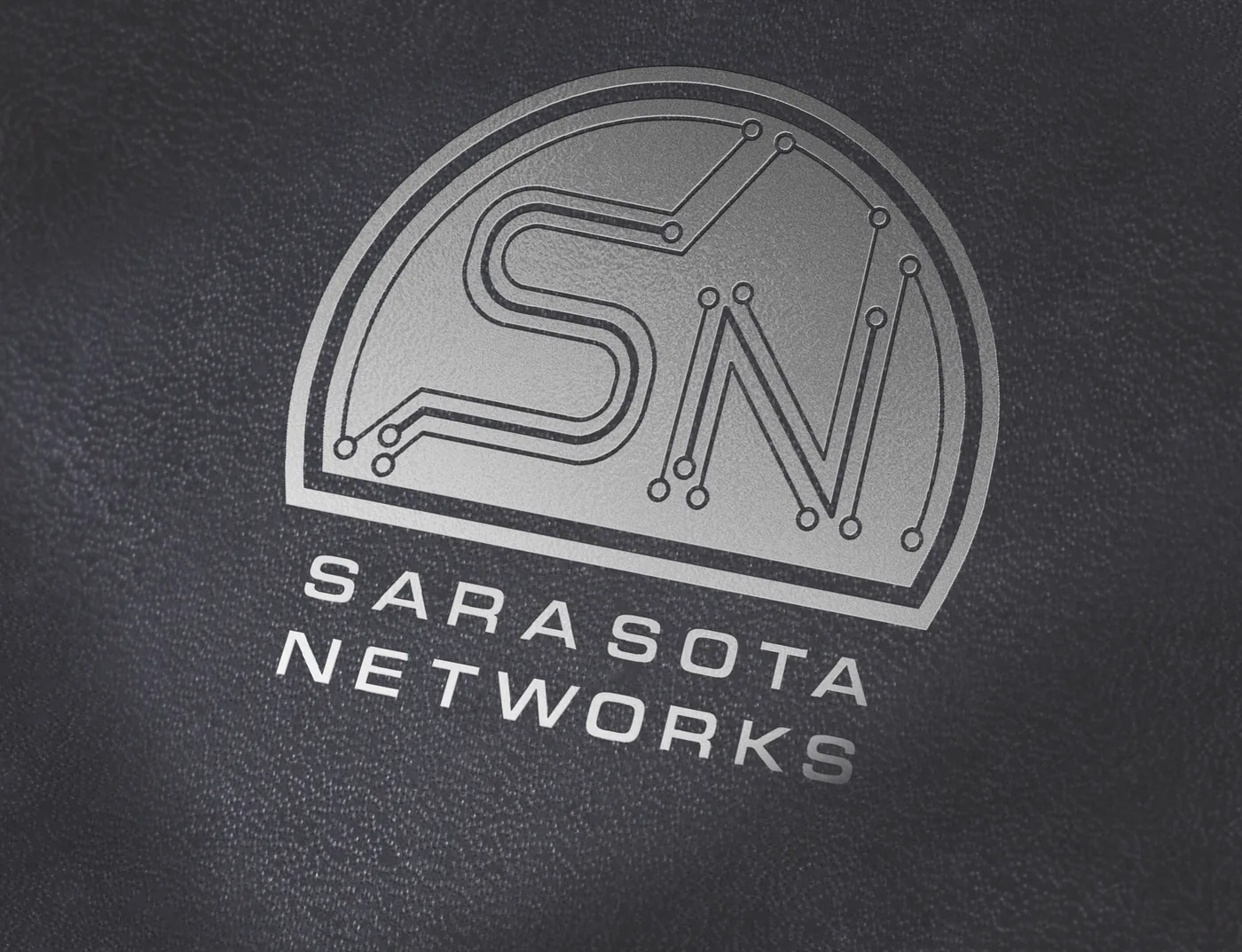 Sarasota Networks logo embossed on a black leather notebook